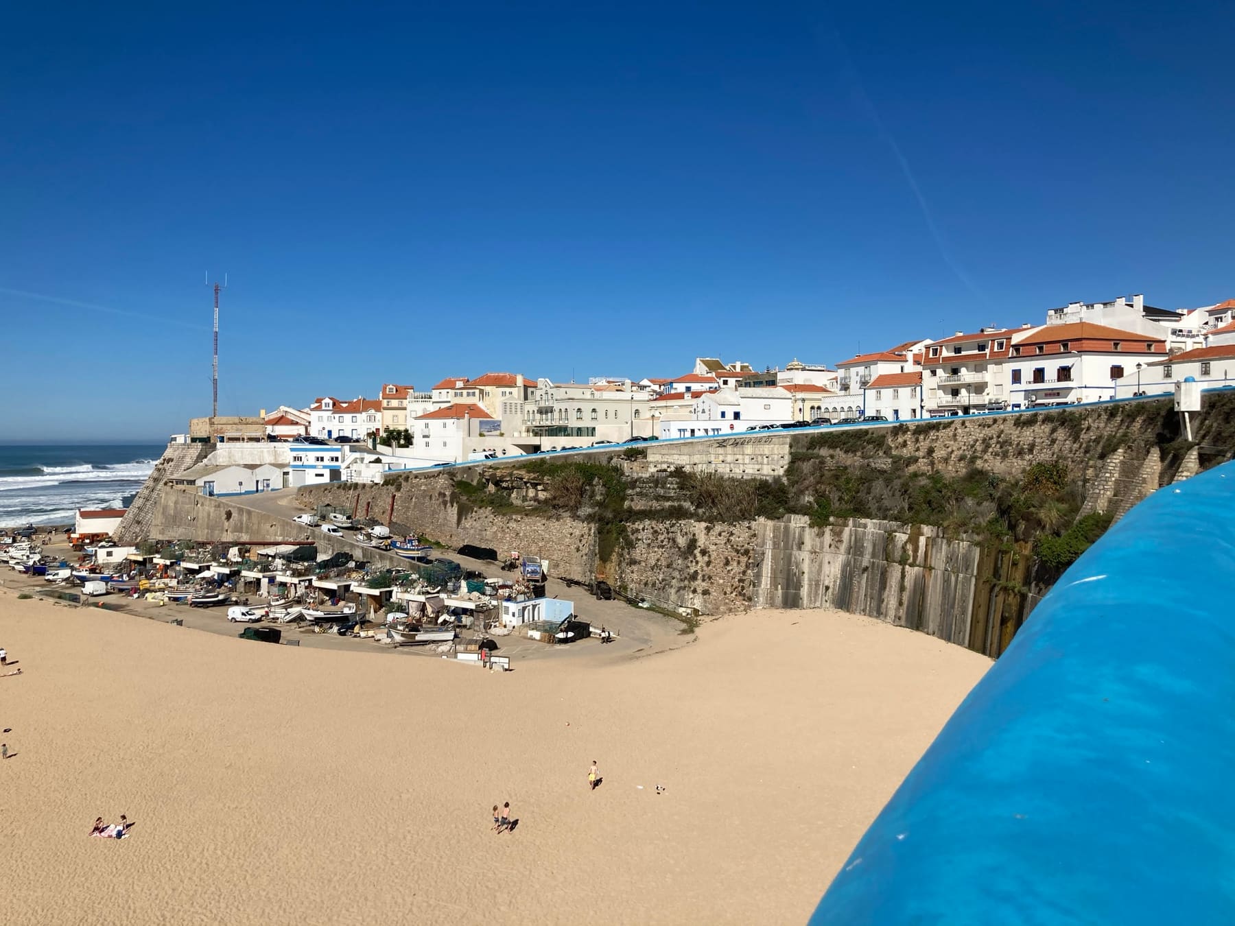 Praia dos Pescadores in Ericeira: a sandy beach with fishing boats below the white old town on the cliff.